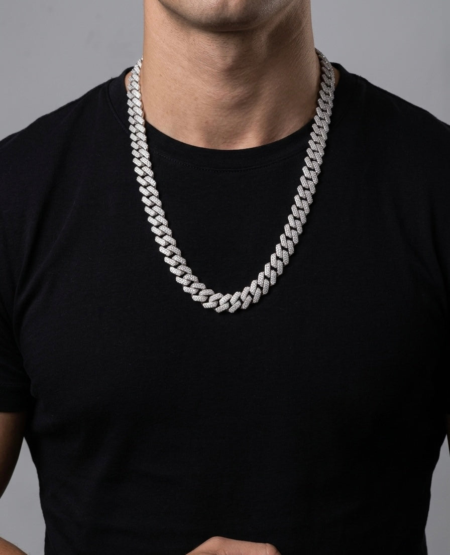 Person wearing a thick silver moissanite chain necklace on a plain background