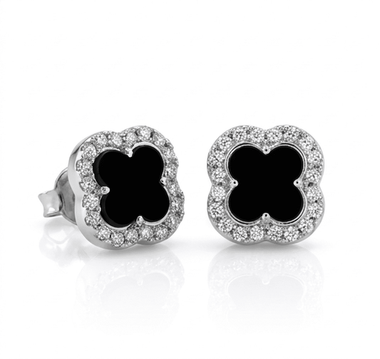 Pair of earrings with black clover-like centers and diamond-studded borders on a white background