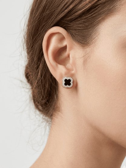 Close-up of a person wearing a black and white floral earring on a light background