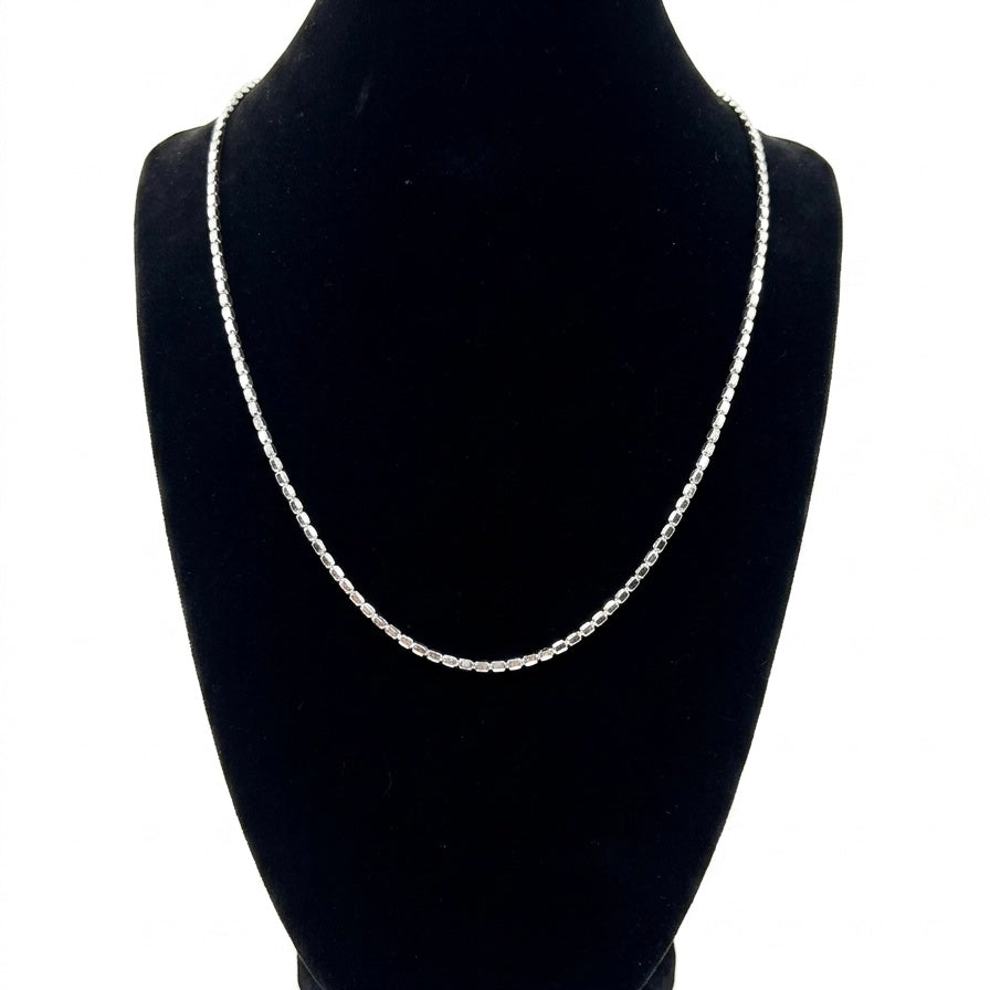 Silver chain necklace on a black mannequin bust against a white background