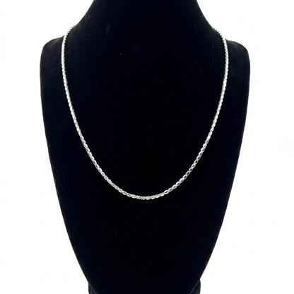 Silver chain necklace on a black mannequin bust against a white background