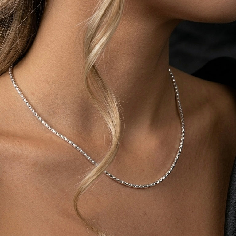 Close-up of a silver necklace on a person with blonde hair.