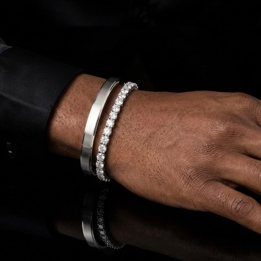 Moissanite tennis bracelet layered with Cartier Love bangle on male model's wrist, sterling silver.