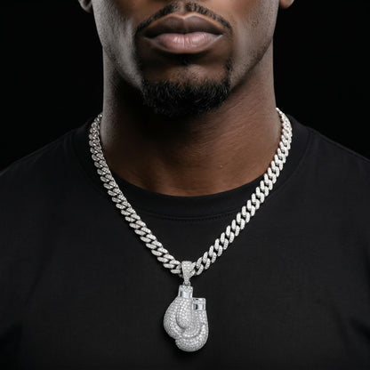 Man wearing a diamond-encrusted chain necklace with a boxing glove pendant on a black background