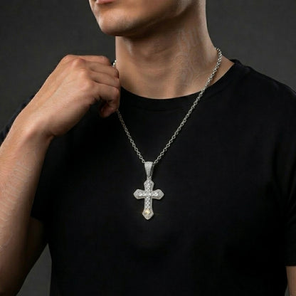 Man wearing a black shirt with a silver moissanite cross pendant necklace against a dark background