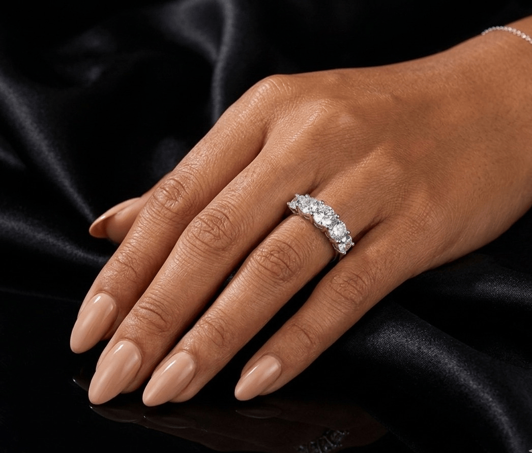 Hand wearing a diamond ring on a black satin background