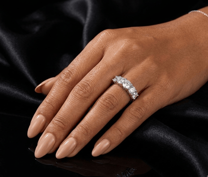 Hand wearing a diamond ring on a black satin background