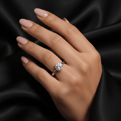 Hand wearing a moissanite ring on black fabric