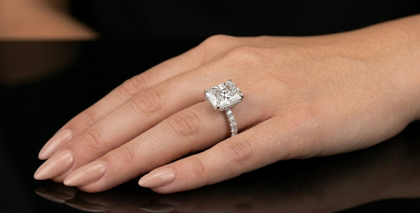 radiant silver moisanite ring on a hand against a dark background