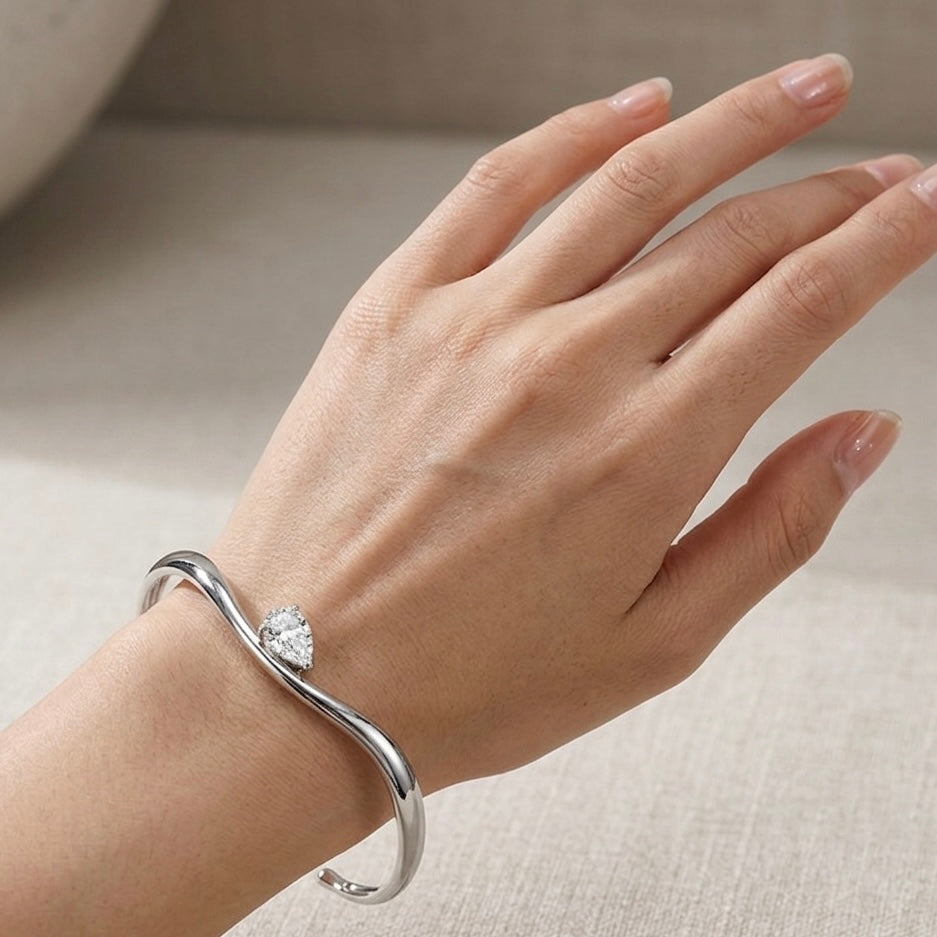 Helena moissanite bangle worn on wrist, 2ct pear main stone in 925 sterling silver lifestyle shot.